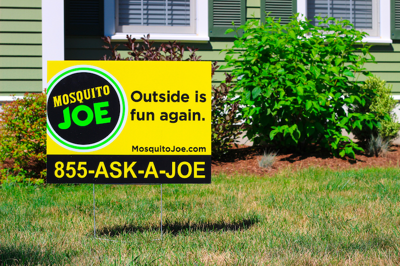 Mosquito Joe yard sign and service van displayed in front a Florida home.