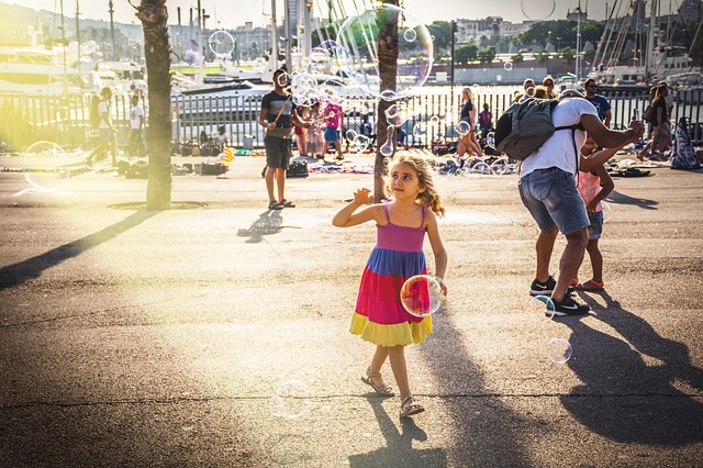 A group of people along with child in a colorful dress playing with bubbles on a pier