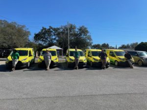  Five Mosquito Joe of Northwest Florida Technicians standing infront of yellow and green Mosquito Joe vans. 